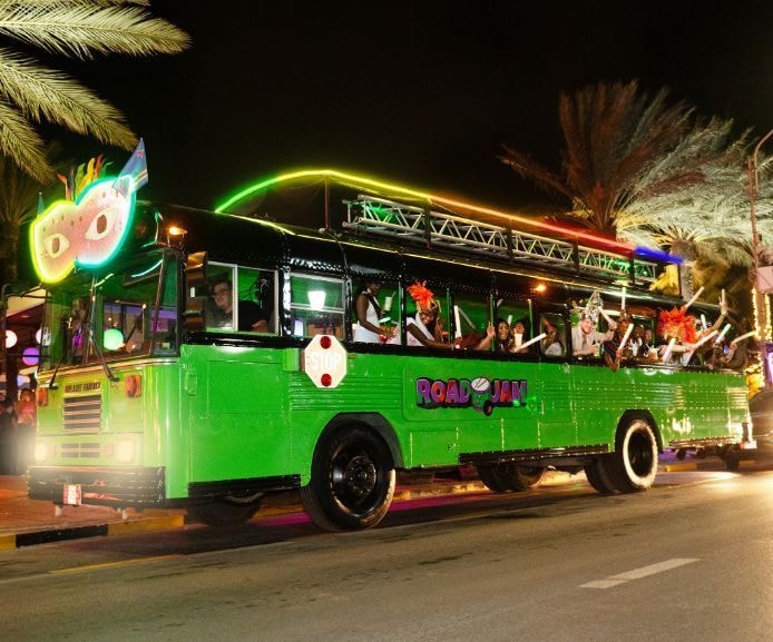 Road Jam party bus lit up at night in Aruba
